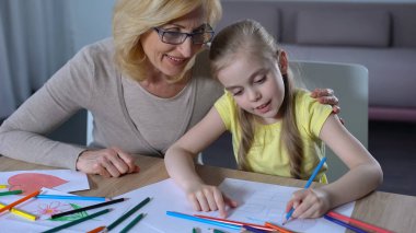 Büyükanne sarılma torunu, renkli kalem ile şirin kız boyama ev