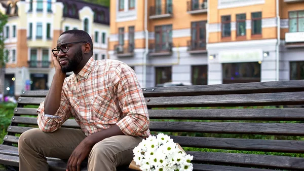 Hayal kırıklığına erkek oturma yalnız çiçek buketi ile şehir bankta, başarısız olan tarihi