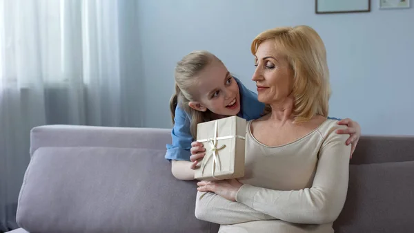 Маленькая Блондинка Представляет Подарок Бабушке Обнимает Отношения — стоковое фото