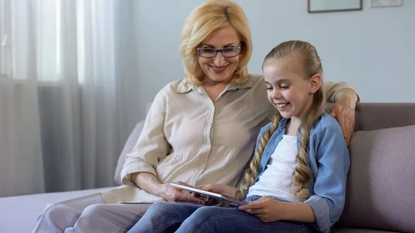 Neta Cabelos Compridos Assistindo Filmes Tablet Com Sua Avó Sofá — Fotografia de Stock