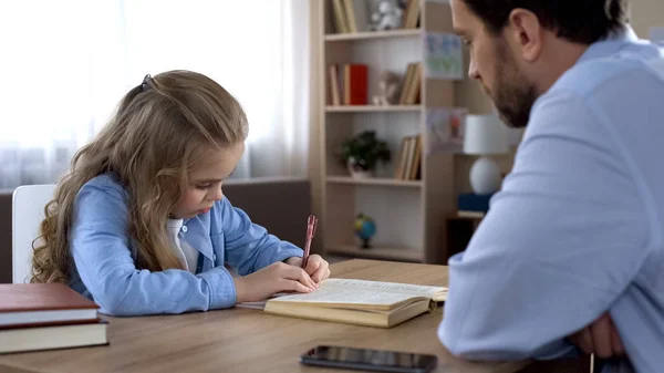 Tiukka Isä Pakottaa Pienen Tyttären Tekemään Kotitehtäviä Koulutusta Perhesuhteita — kuvapankkivalokuva