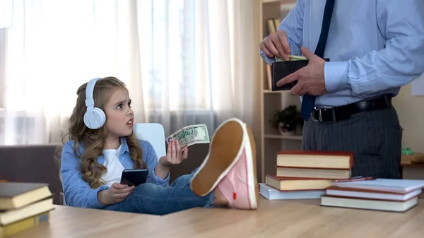 Busy Father Giving Pocket Money Little Capricious Daughter Headphones — Stock Photo, Image