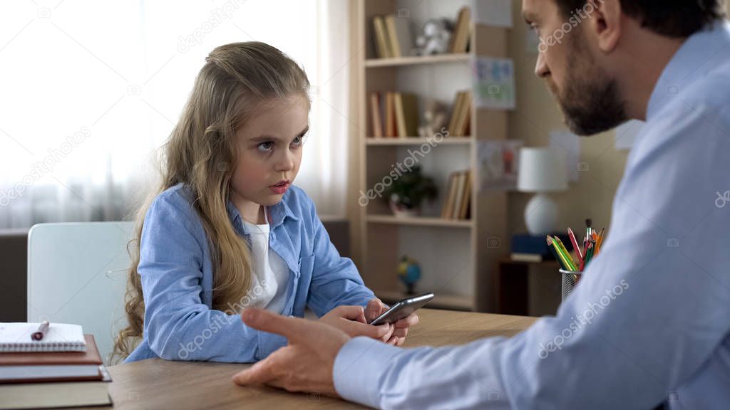 Mischievous daughter playing on smartphone ignoring dad, family conflict