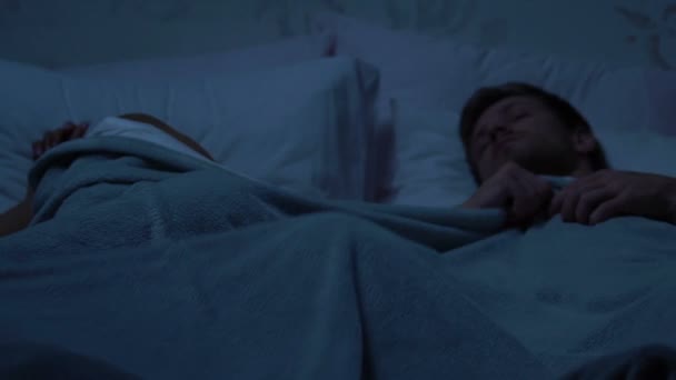 毛布のために戦って 夜関係で大きなベッドで寝ている家族のカップル — ストック動画