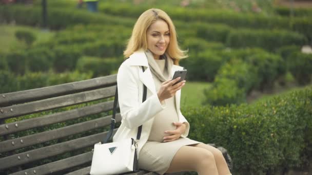 Mujer Embarazada Feliz Sentado Banco Del Parque Con Teléfono Inteligente — Vídeo de stock