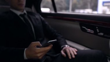 Başarılı bir işadamı lüks otomatik, e-posta uygulaması okuma Smartphone, kaydırma