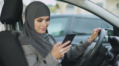 Arabanın içinde otururken, telefon app kaydırma, en iyi yol arama genç Müslüman kadın