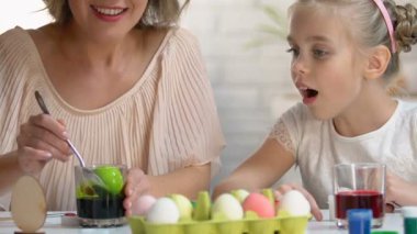Küçük çocuk heyecanla izlerken anne yeşil gıda boyası, Paskalya dekor yumurta ölüyor