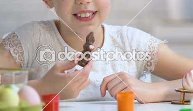 Mutlu küçük kız zevk lezzetli çikolata tavşan, tatlı Paskalya hediyesi, çocukluk