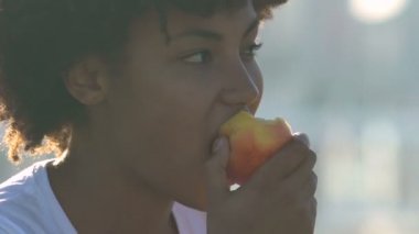 Güzel bir Afrikalı-Amerikalı kadın yeme elma şehir sokak, sağlıklı atıştırmalıklar