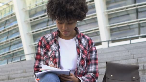 Chica Birracial Pelo Rizado Sentada Las Escaleras Escribiendo Algo Cuaderno — Vídeo de stock