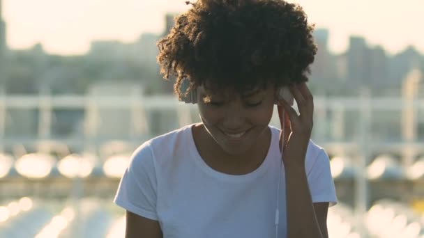 年轻的千禧一代妇女与耳机听音乐和跳舞在街上 — 图库视频影像