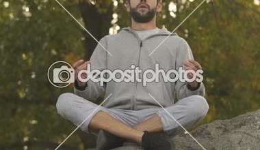 Lotus oturan sportif adam rock üstte, meditasyon getirin ve sakin ol, hobi