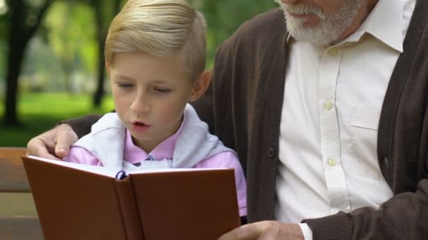 Menino Avô Lendo Livro Relaxando Banco Parque Educação — Vídeo de Stock