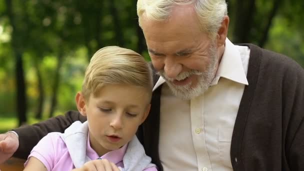 小さな男の子をかける技術スマート フォンを使用して彼の祖父を教える — ストック動画