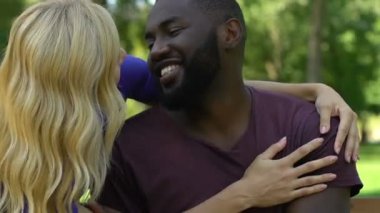 Sarılma, flört karışık yarış çift bankta güneşli günde park, dinlenme Tarih