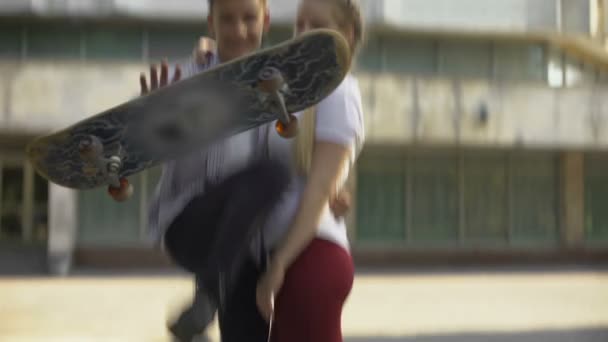 Skater Fazendo Truque Com Placa Abraçando Senhora Olhando Para Câmera — Vídeo de Stock