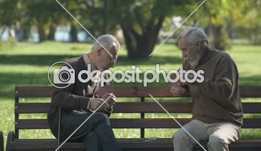 Old men playing cards and having fun in city park, active lifestyle, retirement