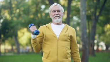 Yaşında yakışıklı Park, boş zaman etkinliği dumbbells ile kol egzersizleri yapıyor