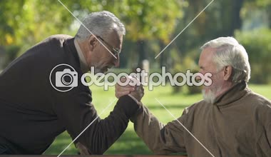 Dışarıda, arm-wrestling olumlu erkekler yaşlı arkadaş birlikte eğleniyor