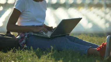 Afrika kökenli Amerikalı öğrenci otururken çimenlikte, laptop, tipik bir proje üzerinde çalışırken