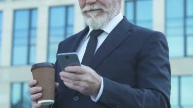 Eski işadamı kahve molası telefon kullanarak sosyal ağ fotoğraflarda kaydırma