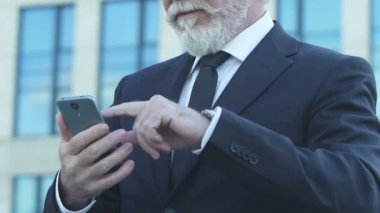 İhtiyar smartphone, kullanarak takım elbiseli app, mutlu duygular kalma fotoğraflar kaydırma