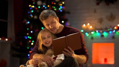 Babam Noel ağacı, sihirli bir atmosfer yakınındaki güzel kızı için kitap okumak