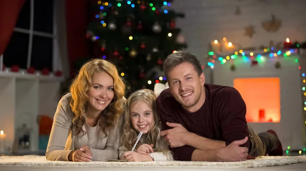年轻的家庭微笑着在镜头 写信给圣诞老人 相信童话故事 — 图库照片