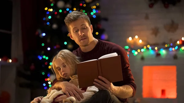 Уважний Тато Читає Різдвяну Казку Сонної Дівчини Біля Прикрашеного Дерева — стокове фото