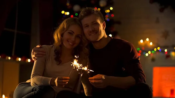 Dulce Pareja Con Luces Bengala Sentada Una Acogedora Habitación Cerca — Foto de Stock