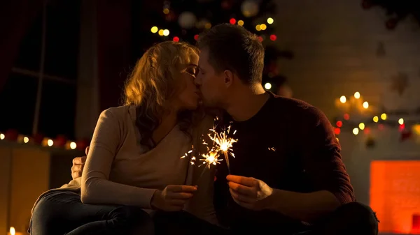若いは ベンガル灯が優しく輝くクリスマス ツリー近くキス カップルします — ストック写真
