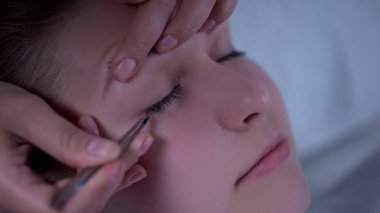 Kirpik uzatma yordamı closeup, sahte kirpikleri istemciye uygulama güzellik uzmanı