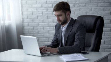 Dizüstü bilgisayar, e-posta yazarak genç emin iş adamı iş sorunları çözme