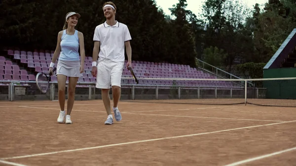 肯定的な笑みを浮かべてカップル トレーニング アクティブなライフ スタイル後テニスコートの上を歩いて — ストック写真