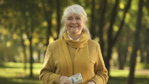 微笑的老太婆在公园里出示一叠美元钞票 计划退休 — 图库视频影像
