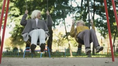 Sallanır park, yaşlı arkadaş, emeklilik zevk iki üst düzey Bayan binmek