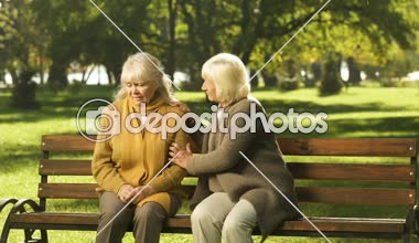 Üst düzey Bayan parkta bankta oturmuş onun kaybı hakkında eski arkadaş rahatlatıcı