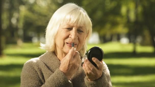 Energetic Senior Woman Using Lipstick Sitting Bench Park Old Age — Αρχείο Βίντεο