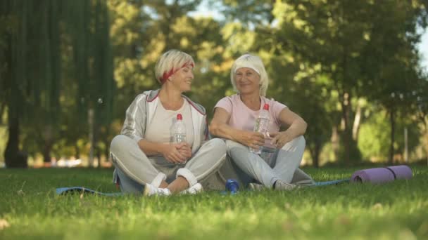Две Женщины Показывают Большие Пальцы Вверх Сидя Траве После Выполнения — стоковое видео