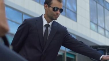 İş kadını, iyi hizmet için arabanın kapısını açarak güneş gözlüğü ciddi güvenlik amacıyla