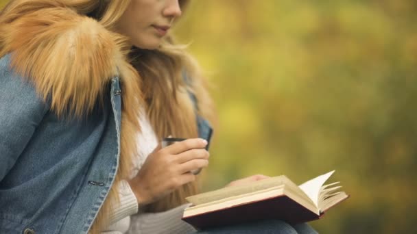 秋の天気 喜びを楽しんで本を読んでとの裏庭でお茶を飲む女性 — ストック動画