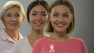 Kameraya, meme kanseri kontrol gülümseyen pembe kurdele ile farklı yaş kadınların