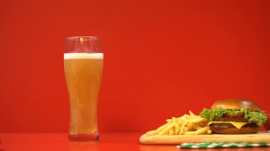 Bira köpük ve hamburger kırmızı arka plan, karbonhidratlar ve yağlı gıdalar