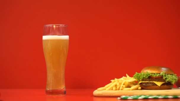 红色背景 碳水化合物和高脂肪食物上的啤酒泡沫和汉堡包 — 图库视频影像