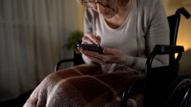 Tekerlekli sandalye GÖRÜNTÜLENMESI smartphone, yaşlı kadında torunları için seviyorum