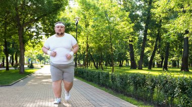 Şişman adam yavaş yavaş açık havada, obezite ile mücadele olarak aktif yaşam tarzı çalışan