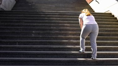Obez kız, hedefe ulaşmak için yorgunluk üzerinde zafer için merdivenleri tırmanmaya zor