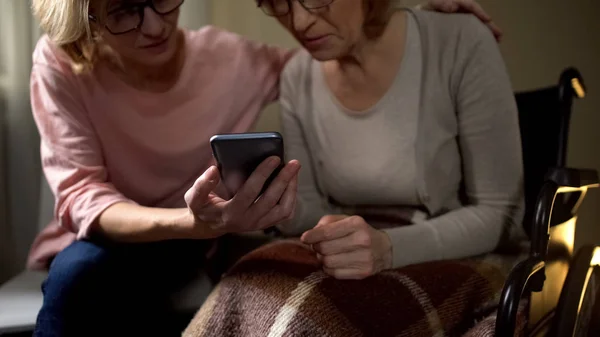 Enkelin Zeigt Ihrer Behinderten Oma Fotos Auf Ihrem Smartphone — Stockfoto