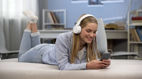 新しいアプリを自宅でリラックスできる音楽を聴くヘッドフォンで若い女性を笑顔 — ストック写真